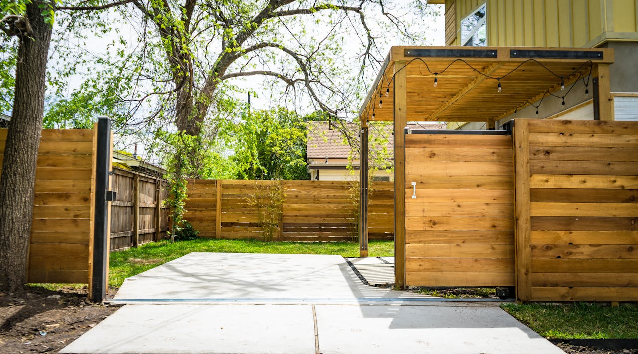 Sunlit wooden fence and patio gate in a peaceful backyard setting.